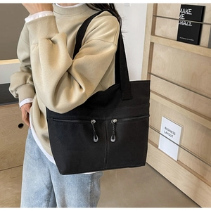 Detail of black canvas tote bag showing dual front zipper pockets and durable fabric texture