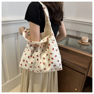 Detail of floral corduroy tote bag with strawberry print worn on shoulder