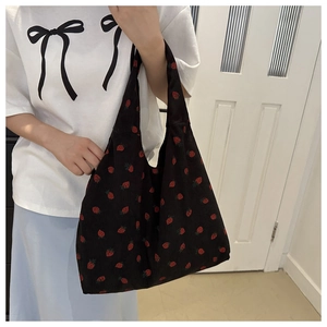 Shoulder shot of corduroy tote bag with red strawberry pattern and black base