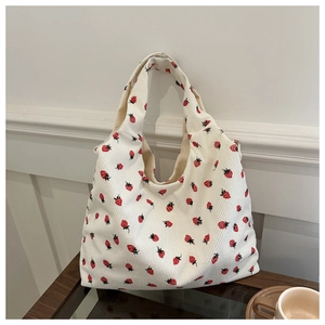 Close-up of cream corduroy tote bag featuring all-over red strawberry print patterns