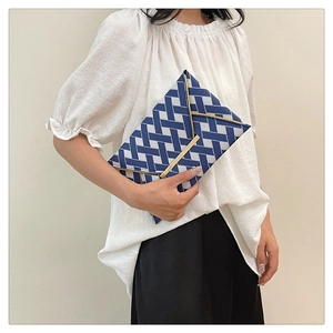 Detail of blue and white geometric checkered envelope clutch with gold metal buckle
