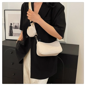 Détail d'un sac beige texture crocodile avec petit porte-monnaie rond sur bandoulière