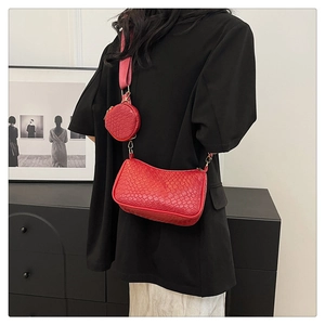 Détail du sac baguette rouge avec texture tressée, porte-monnaie rond et bandoulière