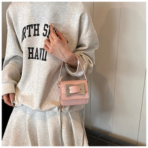 Pink mini crossbody bag with silver buckle and metal chain strap shown on a model