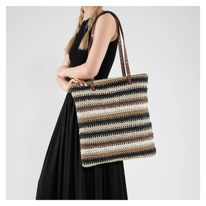 Borsa tote intrecciata a righe colorate con manici in pelle marrone indossata da una modella