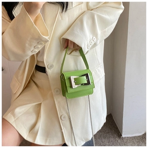 Close-up of bright green mini crossbody bag featuring a large silver square metal buckle