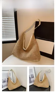 Close-up of a woven straw tote bag featuring white leather trim and hobo shoulder strap