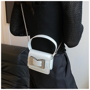 Detail of white mini square bag featuring silver metal buckle and chic chain strap