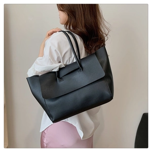 Minimalist black leather tote bag for women shown with casual outfit in a lifestyle setting
