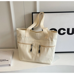 Detail view of large canvas tote bag with front zipper pockets and wide shoulder straps