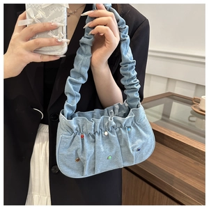 Detailed shot of light blue denim bag with colorful studs and pleated handle details