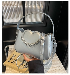 Detail of silver crossbody bag with metallic heart emblem and silver bead chain trim