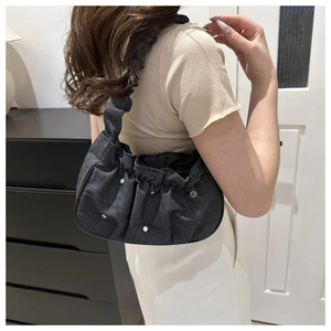 Detail of dark denim pleated shoulder bag with colorful gemstone and pearl embellishments