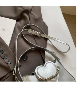 Detailed view of silver heart-shaped patch and metal beads on fashion square crossbody bag