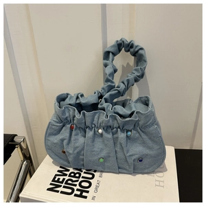 Detail of light blue denim pleated bag featuring vibrant colorful beaded decorations