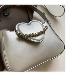 Detailed view of silver heart-shaped handbag with metallic leather and bead handle