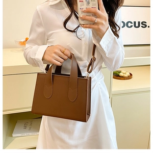 Sac fourre-tout minimaliste en cuir marron pour femme présenté par un mannequin