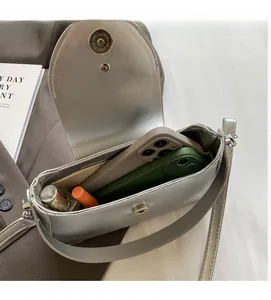 Interior view of a metallic silver crossbody bag showing capacity for phones and makeup