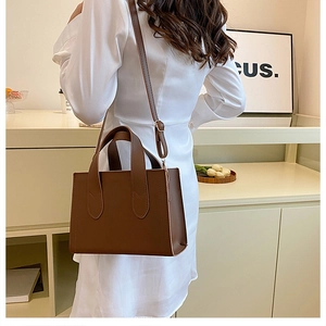 Sac fourre-tout en similicuir marron foncé avec poignées porté par un mannequin chic