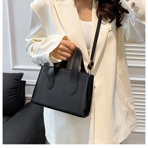 Détail d'un sac cabas noir minimaliste avec ferrures dorées et bandoulière amovible