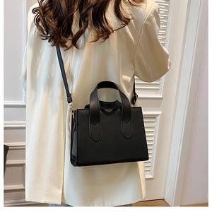 Détail du sac à main noir minimaliste avec bandoulière et finitions dorées chic