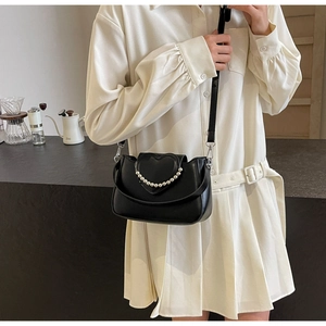 Detail of black saddle bag featuring heart relief and elegant pearl handle strap