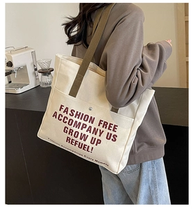 Detail of canvas tote bag with brown straps and red slogan printed on cream fabric