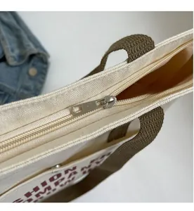 Detailed view of the smooth silver zipper closure and canvas fabric on the tote bag