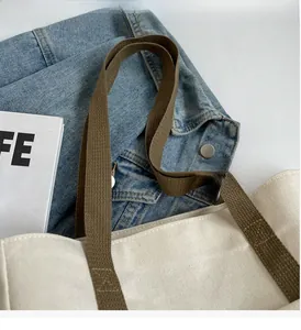 Close-up of durable olive green handles with reinforced stitching on a beige tote bag
