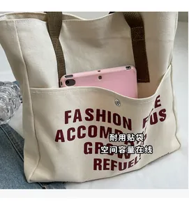 Close-up of cream canvas tote bag with red lettering and durable brown shoulder straps