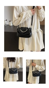 Close-up of black heart-shaped flap shoulder bag with decorative pearl chain detail
