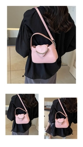 Detailed close-up of pink heart-shaped bag with silver bead chain and leather texture