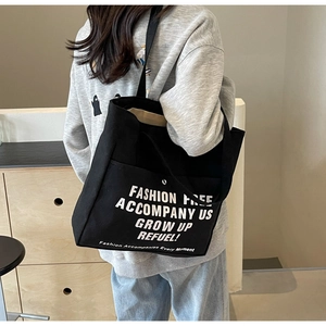 Detail of black canvas tote bag showing large capacity and white fashion letter print