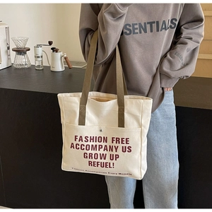 Detail of canvas tote bag showing front pocket with snap button and vintage lettering