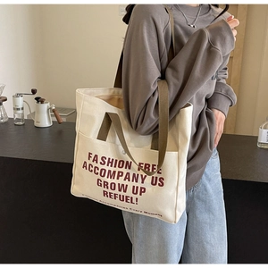 Detail of canvas tote bag with side pocket and brown shoulder straps in urban lifestyle setting