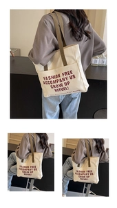 Detail of canvas tote bag showing large front pocket and brown shoulder straps