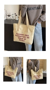 Detail of canvas tote bag with large red lettering, front pocket, and metal snap button