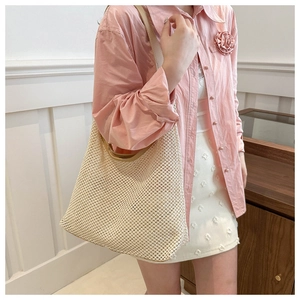 Hollow straw tote bag with brown leather straps shown on a model for summer style
