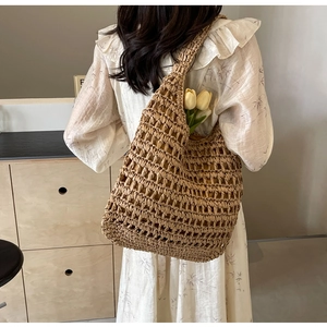 Detail of hand-woven hollow straw shoulder bag with natural mesh texture and tulip inside