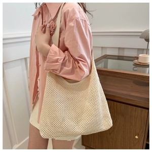 Detailed view of beige woven tote bag showing hollow mesh texture and smooth strap