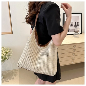 Detail of woven mesh texture and contrast leather trim on a large straw shoulder bag