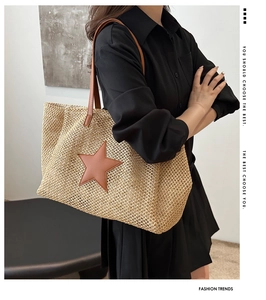 Detail of woven straw tote bag featuring a leather star patch and long shoulder straps