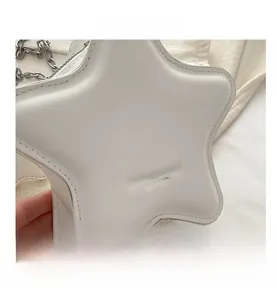 Close-up of white star-shaped bag showing embossed fashion text and silver chain strap