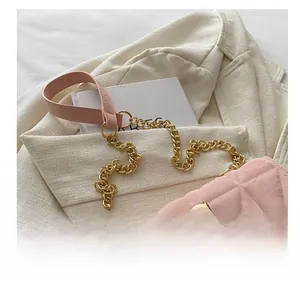 Detail of pink quilted crossbody bag with chunky gold chain and textured suit backdrop