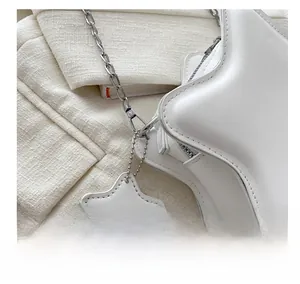 Detail of silver chain hook and star-shaped leather tag on white star crossbody bag
