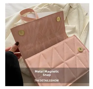 Detailed view of pink quilted handbag showing the metallic magnetic closure buckle