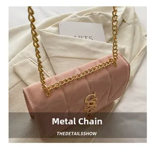 Detailed shot of pink quilted crossbody bag with gold chain and SS logo on ivory blazer