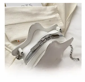 Detailed close-up of smooth silver dual zippers on a white star-shaped crossbody bag