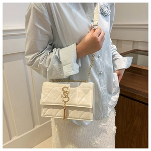 Detail of cream quilted chain bag with gold S-shaped hardware and elegant fringe