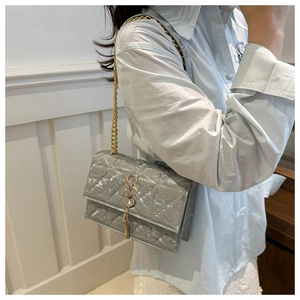 Detail of silver chain bag with quilted texture and gold metal tassel buckle charm